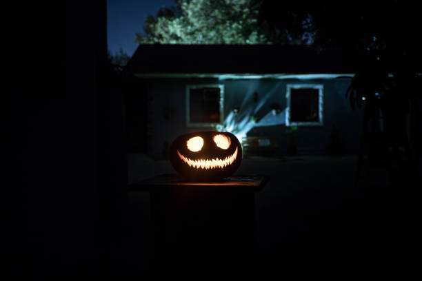 istock Pumpkin Burning In Forest At Night - Halloween Background. Scary Jack o Lantern smiling and glowing pumpkin with dark toned foggy background. Selective focus 1432560958