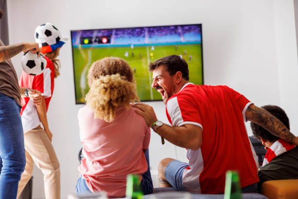 istock Friends cheering while watching football on TV 1432562180