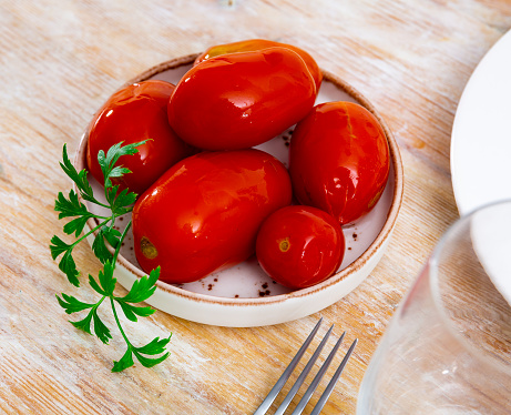 Marinated tomatoes served on white plate decorated with parsle, homemade preserves