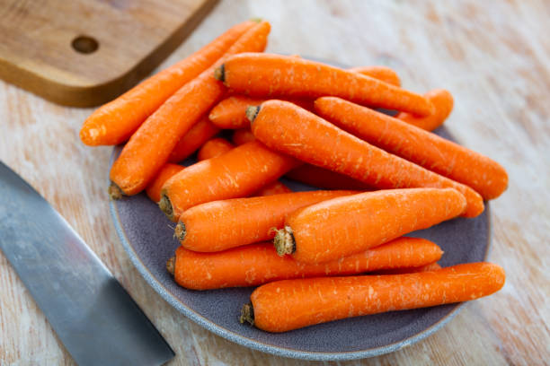 istock Plate of fresh carrots on wooden table 1432563315