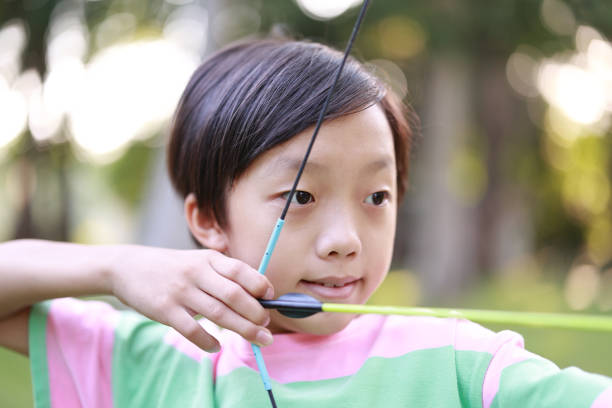 Little boy shooting bow in forest