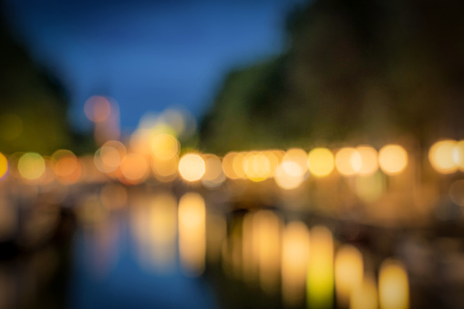 A deliberately defocused image of a traditional canal in Amsterdam, Holland at dusk, with the street lights reflecting in the water of the canal.