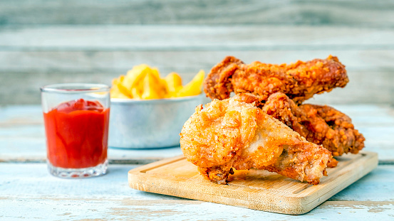 Close-up of Fried chicken food and Fried Chicken Drumsticks wite french fries and tomato ketchup on a wooden table