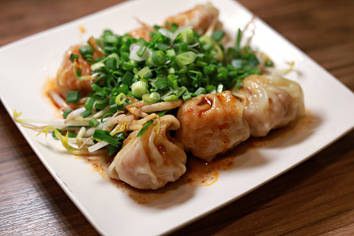Asian dumplings Jiaozi served in a bowl of chili oil sauce