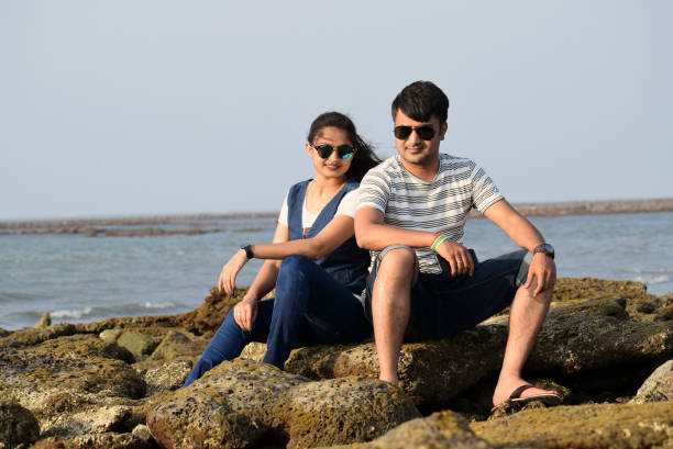 pareja asiática recién casada sentada en el coral de una playa de mar que pasa por un tiempo romántico. - honeymoon beach couple heterosexual couple fotografías e imágenes de stock
