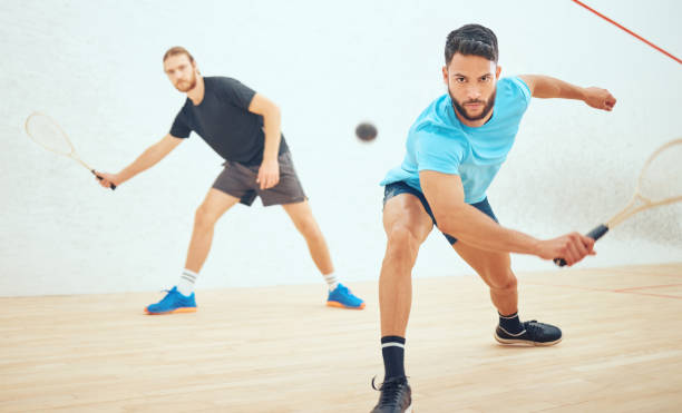 istock Two athletic squash players playing match during competitive court game. Fit active mixed race and caucasian athlete competing during training challenge in sports centre. Sporty men in championship 1432573852