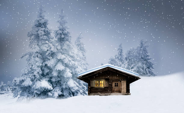 capanna di tronchi con finestra illuminata e abeti dalle nevicate di stagno inverno - hut winter snow mountain foto e immagini stock