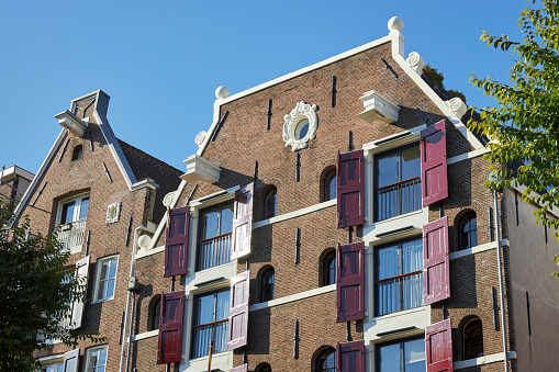 Canal house facade with red window shutters in Amsterdam, The Netherlands