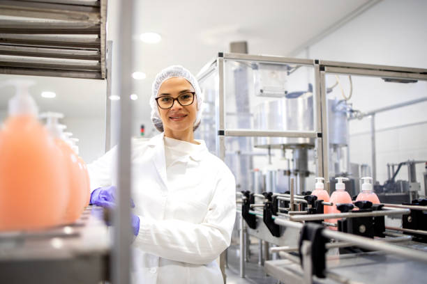 técnica tecnóloga femenina de pie dentro de la fábrica de fabricación que produce productos químicos de limpieza para uso doméstico e industrial. - industry portrait production line factory fotografías e imágenes de stock