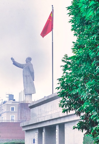 Chengdu, China - November 28 2009 : a huge statue of Mao waving on top of a building with the chinese flag next to it.
