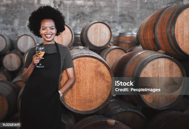 Portrait Of A Young Woman Winemaker Standing With A Glass With Wooden Barrel Of Red Wine In A Winery Cellar Or Distillery Entrepreneur Or Business Owner Working For Startup Success Business Success Stock Photo - Download Image Now