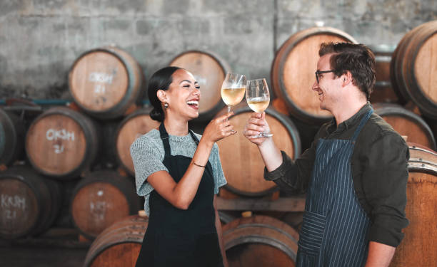 vino, bicchiere e brindisi con una coppia che beve alcolici in cantina, distilleria o cantina insieme. agricoltura, collaborazione e lavoro di squadra con un uomo e una donna che bevono e fanno un applauso come una squadra - winemaking vintner winery people foto e immagini stock