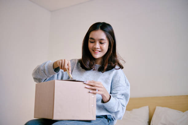 istock Beautiful Asian Woman Opening Packaging Parcel at Home 1432584845
