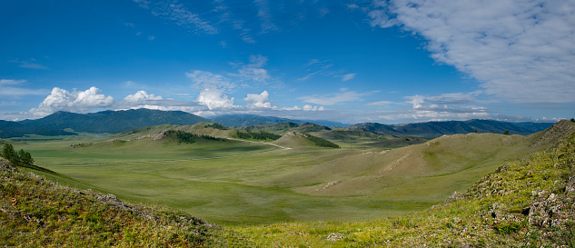 Russia. South of Western Siberia, Mountain Altai.  Picturesque hilly mountains covered with a solid green carpet with many alpine flowers near the village of Ust-Kan.