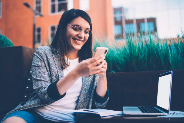 istock Overjoyed young freelance woman using smartphone in street 1432587869