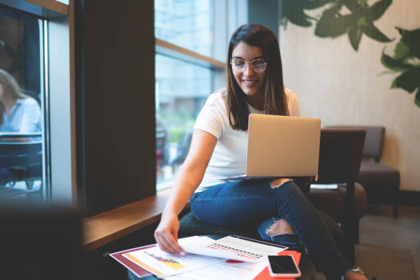 fröhliche junge frau, die an einem diplom im college-zimmer arbeitet - online degree stock-fotos und bilder