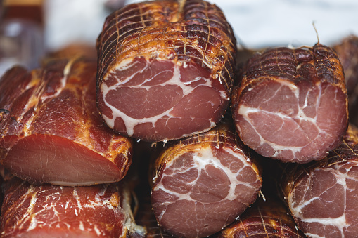 Various types of ham at a market. Slices of different smoked ham displayed on the market stand. Selective focus