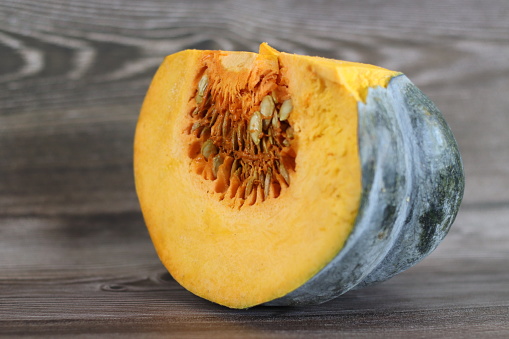 Sliced pumpkin. A pumpkin is a cultivar of winter squash that is round with smooth, slightly ribbed skin, and is most often deep yellow to orange in coloration. Shot on rustic wooden background