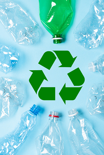 Plastic bottles with recycling symbol on blue background top view