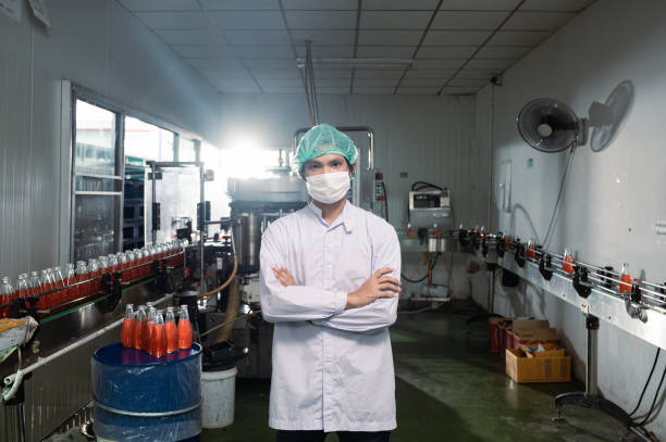 istock Asian supervisor man in sterile suit standing with bottled production line in beverage processing factory 1432590868
