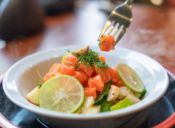Spicy sliced salmon with fruit salad in white ceramic bowl stock photo