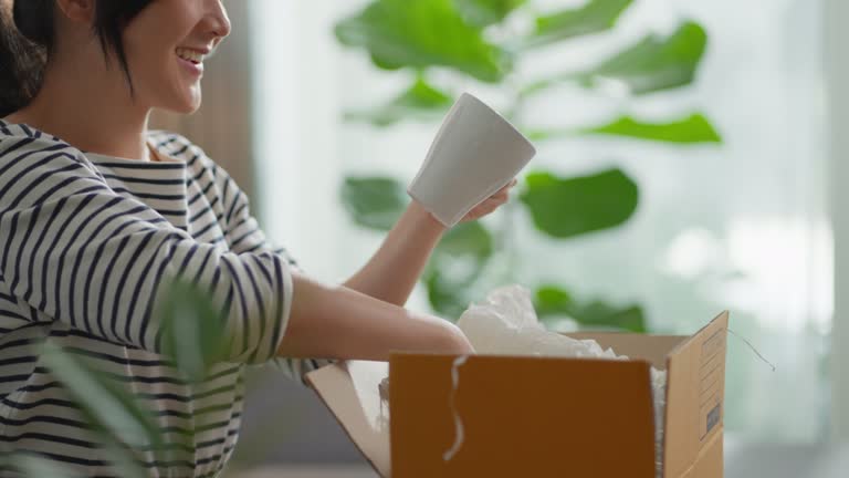 Asian woman opening carton box from shopping online home decoration unpack and checking product.