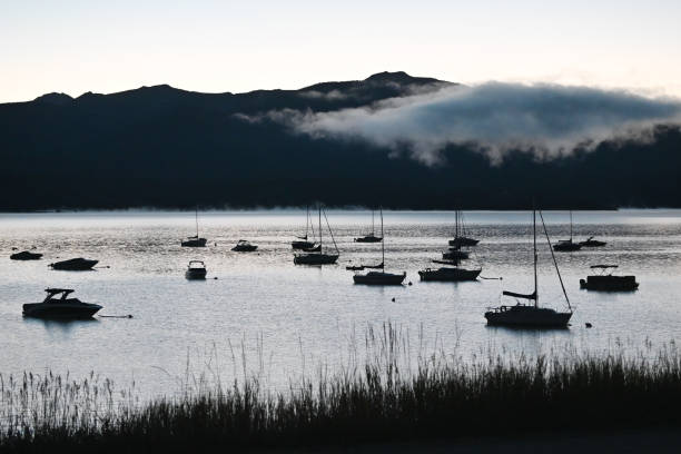 Silhouetted boats in marina before sunrise.