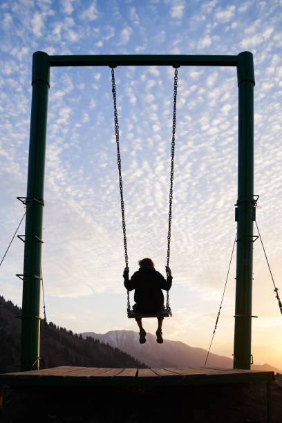 istock Young man is riding on a swing in mountains during a sunset. 1432592833