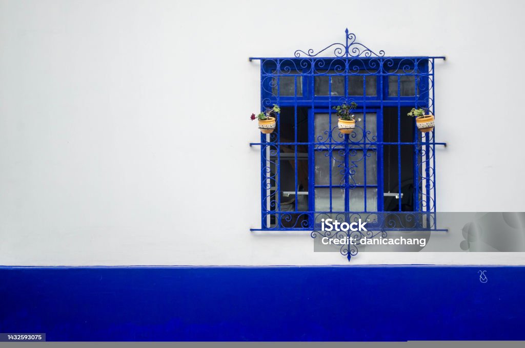 An ornate window painted blue against a vibrant white and blue wall An ornate window painted blue against a vibrant white and blue wall in Lima, Peru Blue Stock Photo
