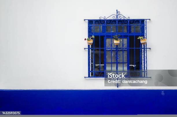 An Ornate Window Painted Blue Against A Vibrant White And Blue Wall Stock Photo - Download Image Now