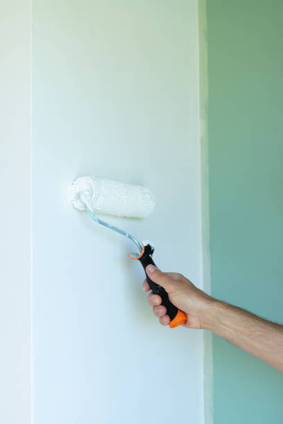 istock Painting the wall with a roller. Man hand with paint roller. Vertical photo. 1432593230