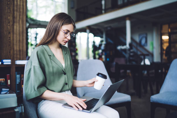 istock Pretty woman drinking coffee and using laptop 1432593341