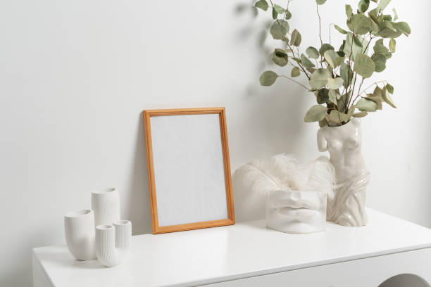 istock Wooden vertical frame with white vase of eucaliptus leaves over white wall 1432594921