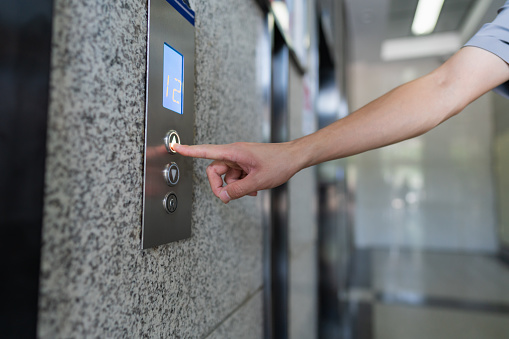 A hand pressing an elevator button