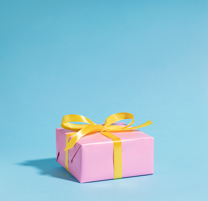 Pink gift box with yellow ribbon on blue. This file is cleaned and retouched.