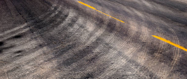 istock Tire Tracks Turning on Road with Yellow Stripe Lines 1432597207