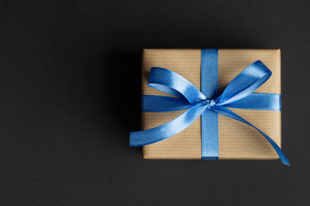 istock Gift box with blue ribbon on black 1432597309