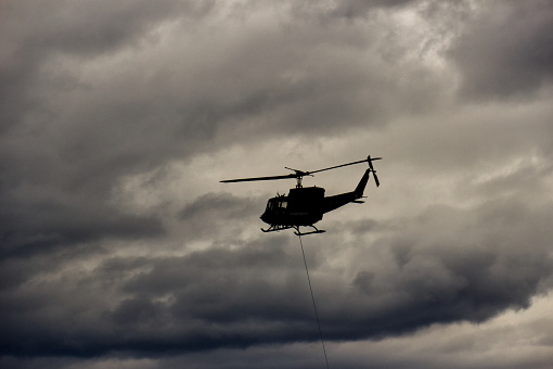 Military helicopter flying over dramatic cloud formation