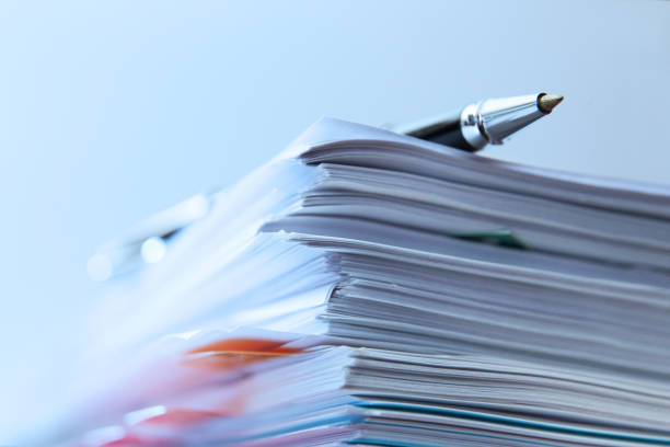 Ballpoint Pen Resting On Top Of Stack Of Documents A ballpoint pen rests on top of a stack of documents ready for signing. The image is photographed using a very shallow depth of field with the focus being on the tip of the pen. legal document stock pictures, royalty-free photos & images