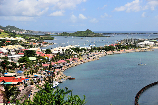 Marigot, Collectivity of Saint Martin / Collectivité de Saint-Martin, French Caribbean: view over the capital of French Saint Martin - west coast of the island of Saint-Martin, along the bays of Marigot and Nettlé, and the hills of the interior of the island, to the east. In the background the Simpson Bay lagoon and Princess Juliana International Airport in Dutch Sint Maarten.