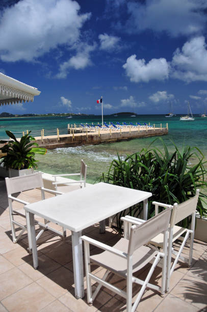 Marigot, Collectivity of Saint Martin / Collectivité de Saint-Martin, French Caribbean: waterfront table and pier with deckchairs and the French flag, beach on Marigot bay.