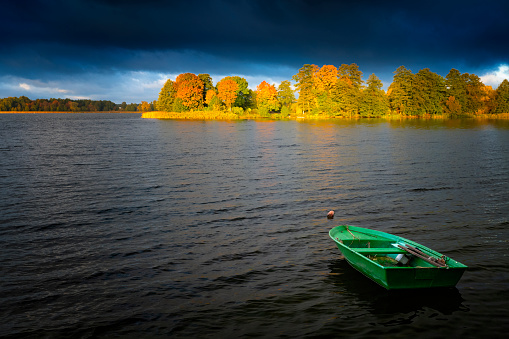 Boat floating on dark waters of autumn lake. Masuria, Poland.