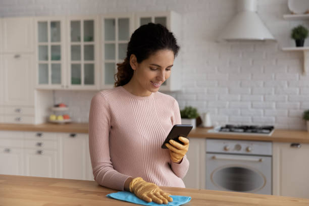 istock Smiling woman housewife using smartphone, distracted from cleaning 1432616206