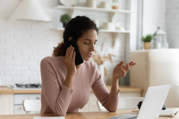 istock Confident woman making phone call, sitting at table in kitchen 1432616212
