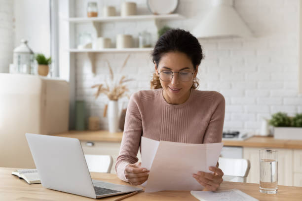 istock Smiling woman in glasses working with documents, using laptop 1432616214
