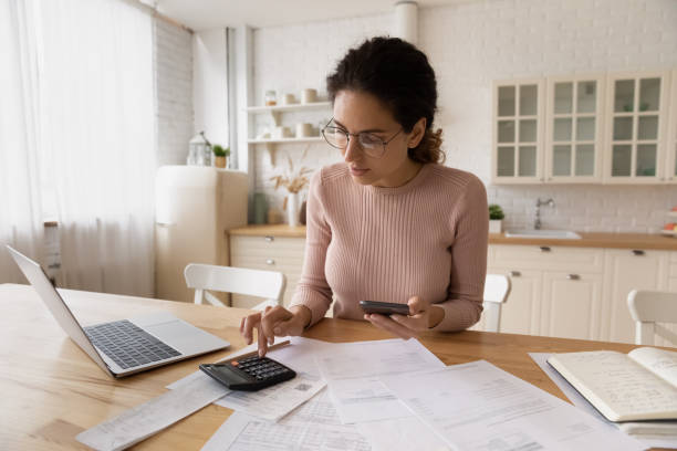 istock Confident woman in glasses calculating budget, using smartphone and calculator 1432616236