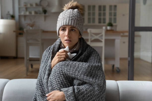 istock Sick woman covered with blanket caught cold, sitting on couch 1432616283