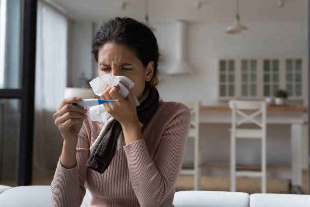 istock Close up sick woman blowing nose, holding digital thermometer 1432616287