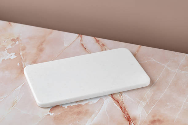 istock Empty blank white cutting board on beige pink marble background. Minimalist mock up for product presentation. 1432616850