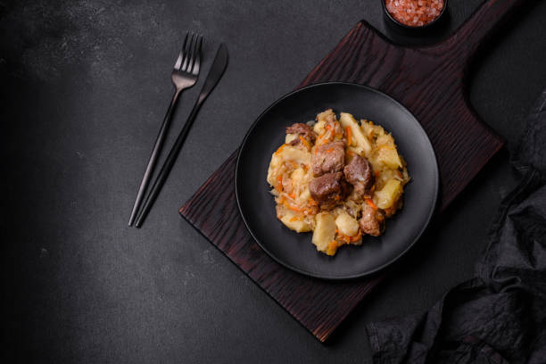 istock Delicious vegetable stew with beef, potatoes, carrots and cabbage in a black plate 1432619316